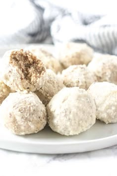 a white plate topped with snowball cookies on top of a marble countertop next to a gray and white towel