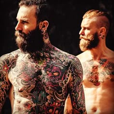 two men with tattoos on their body standing next to each other and looking off into the distance