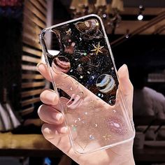 a person holding up a clear case with planets and stars in the sky on it