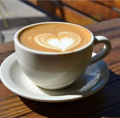 a cup of coffee on a saucer with a heart pattern in the foamy liquid