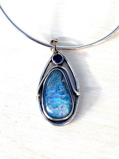 I did the silversmith work on this amazing pendant. It has an amazing opal at 54 carats.  I set this in a unique silversmith style I learned recently from an a wonderful silversmith teacher.  The top stone is a man-made faceted blue sapphire.  It can be changed up as you desire.  If you want the bail changed - I can do this.  I made the bail from a 20 gauge silver piece of wire.   You can request a silver extension length chain or a pre-fashioned silver piece to fit closely around the neck.  Is organic and beautiful.  I have to admit I was stunned at how beautiful it came out. Opal Large Pendant Jewelry, Polished Opal Pendant Jewelry, Blue Opal Pendant Jewelry, Edison Pearls, Lady Of Fatima, Idaho Falls, Rosary Bracelet, Statement Pendant, Glass Beaded Bracelets