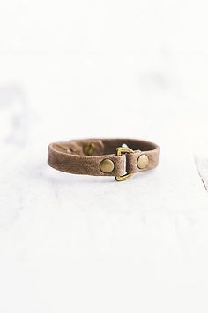 a brown leather bracelet with two gold buttons