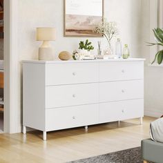 a white dresser in a living room next to a window