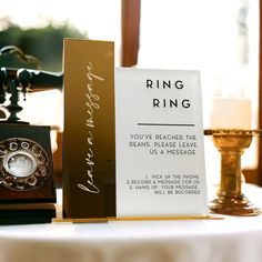 a table topped with an old fashioned phone next to a sign that reads ring ring you've reached the deans, please leave us message