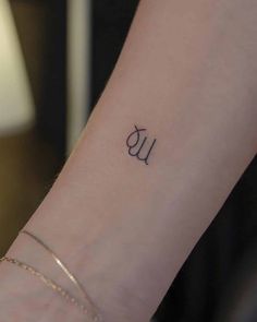 a woman's wrist tattoo with the letter u in cursive writing on it