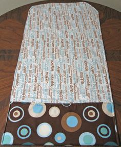 a brown and blue polka dot table runner on top of a wooden table next to a white wall