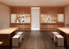 two chefs are preparing food in a large room with wooden shelves and benches on the floor