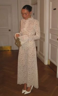 a woman in a white dress is looking down at her purse while standing on the floor