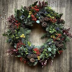 a wreath with pine cones, berries and greenery on a wooden background for christmas