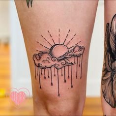 a woman's leg with tattoos on it and the sun in the clouds above her