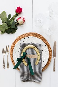 a place setting with napkins, flowers and silverware on a white wooden table