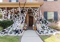 a house decorated for halloween with spider webs and pumpkins