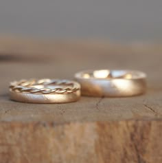 two gold wedding rings sitting on top of a wooden table