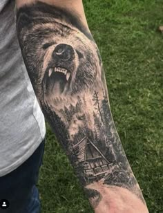 a man's arm with a bear and cabin in the woods tattoo on it