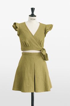 Elevate your style with our Green Ruffle Top and Pleated Skirt Set, a masterpiece in sustainable fashion. This two-piece set exudes innate elegance, from the playful ruffle top to the meticulously pleated skirt that adds sophisticated texture to both the front and back. Crafted with exceptional dedication, the high-quality linen selected promises not just a soft touch but durability that honors traditional craftsmanship. 🍃 With an elegant tie closure, the top offers a customizable fit and a tou Fitted Cotton Skirt Set For Summer, Chic Summer Skirt Set With Short Sleeves, Two-piece Short Sleeve Crop Top For Spring, Green Matching Set Tops For Spring, Chic Cropped Two-piece Set For Spring, Spring Two-piece Crop Top Sets, Chic Green Cotton Sets, Green Two-piece Dress For Spring, Chic Green Matching Set