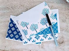 two envelopes with blue and white designs on them, one has a pen next to it