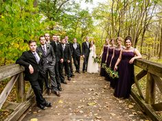 a group of people standing on top of a wooden bridge in the woods next to each other