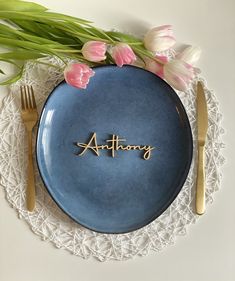 a blue plate with the word anthony written on it next to some pink tulips