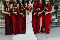 a group of women standing next to each other wearing red dresses and holding bouquets