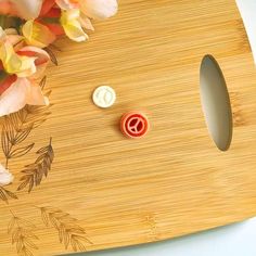 a wooden cutting board with flowers and buttons on it