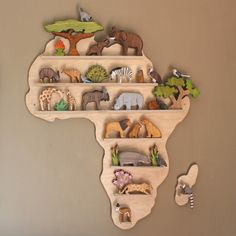 a wooden africa map with animals and trees on the top shelf is mounted to the wall