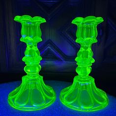 two green glass candlesticks sitting on top of a table