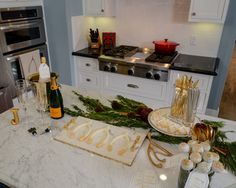 the kitchen counter is decorated with gold and white decorations, including candles, wine glasses, champagne bottles and other holiday decor