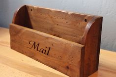 a wooden mailbox with the word mail written on it sitting on a wood table