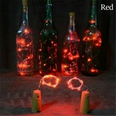 several bottles with lights in them sitting on a table next to some corks and wire