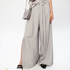 Grey ‘Tami’ Trousers From Allsaints. Tied At The Back, This Wide Leg Design Features A Zip Fastening, Drawstrings, Two Front Slip Pockets And High Side Slits. Chic Split Wide Leg Pants For Spring, Silver Wide Leg Bottoms For Summer, Chic Spring Wide Leg Pants With Split, Elegant Silver Pants For Workwear, Elegant Split Pants For Summer, Silver Bottoms For Spring Formal Occasions, Chic Silver Bottoms For Formal Occasions, Elegant Split Summer Pants, Silver Formal Bottoms For Spring