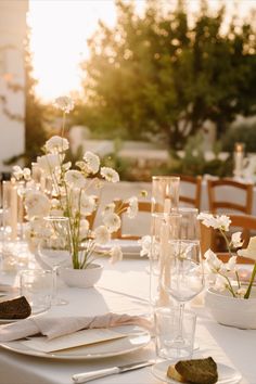 the table is set with white flowers and place settings