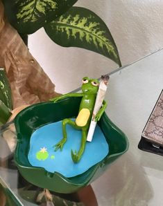 a frog figurine sitting on top of a green plant