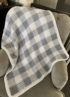 a gray and white checkered blanket sitting on top of a chair next to a window