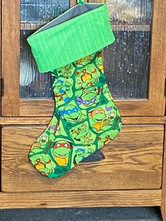 a green stocking hanging from the side of a wooden cabinet