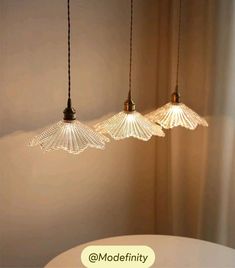 three lights hanging from the ceiling in a room with white walls and curtains behind them