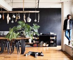 a man standing in an open kitchen next to a table with potted plants on it