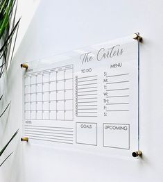 a calendar hanging on the side of a white wall next to a potted plant