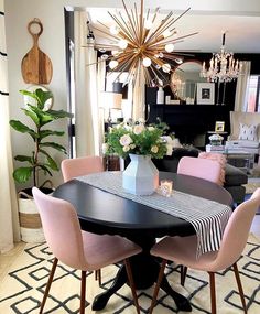 the dining room table is set with pink chairs and a chandelier above it