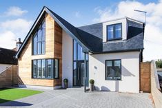 a white house with black roof and windows on the side of it's driveway