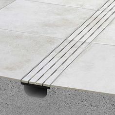 a concrete bench sitting on top of a cement floor next to a sidewalk with metal bars