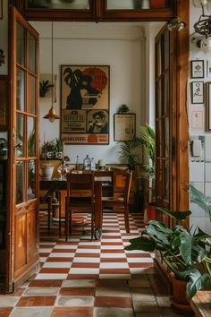 a dining room filled with lots of plants and pictures hanging on the wall above it