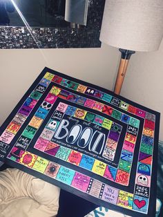 a colorful board game sitting on top of a bed next to a lamp and mirror