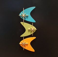 three colorful wind chimes hanging on a black wall in the shape of an arrow