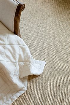 an unmade bed sitting on top of a carpeted floor next to a wooden headboard