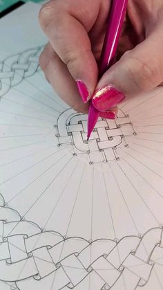 a woman's hand holding a pink pen and drawing on paper