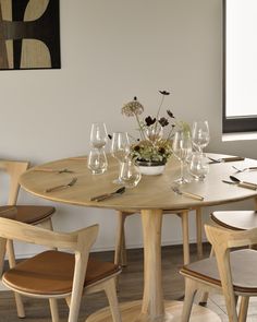 a wooden table topped with lots of wine glasses and vase filled with flowers on top of it