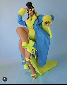 a woman in yellow and blue is sitting on a chair with her legs crossed out