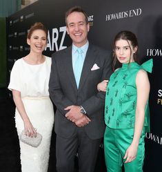 three people standing next to each other on a black carpet