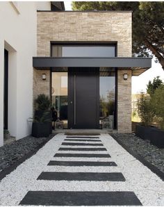 a modern house with black and white stripes on the walkway leading to the front door