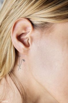 a woman's ear with a cross tattoo on it